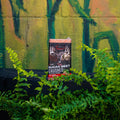 A bag of Deer Hunter Sugar Beet Crushed flavor salt block on a black table in front of a green and yellow painted wall, surrounded by lush green ferns.