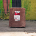 A large rectangular block of Champion's Choice Trace Mineral Salt sits on a weathered wooden deck in front of a colorful, blurred painted brick wall.