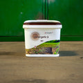 A white plastic tub of Penergetic b WV lawn treatment with a brown lid, set on a concrete floor against a green wall.