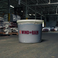 Tub of Wind and Rain Cattle Mineral with a warehouse in the background