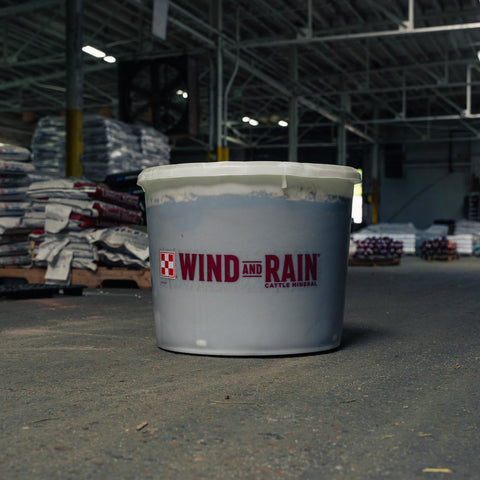 Tub of Wind and Rain Cattle Mineral with a warehouse in the background