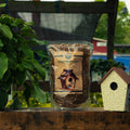 A bag of Dried Mealworms by Bird Pro is displayed on a wooden surface next to a decorative birdhouse, with a garden background.