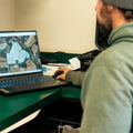 Person using a laptop with a map on the screen at a desk.