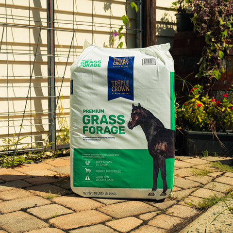A bag of Triple Crown Premium Grass Forage sitting on a patio with plants in the background