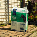 A bag of Triple Crown Premium Grass Forage sitting on a patio with plants in the background