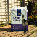 A bag of Triple Crown Safe Starch Forage sitting on a patio with plants in the background