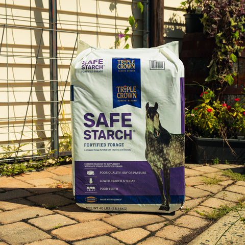 A bag of Triple Crown Safe Starch Forage sitting on a patio with plants in the background