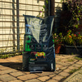 A large black bag of ProForce Fuel supplement stands on a paved patio in front of a garden fence and trellis, with plants visible in the background.