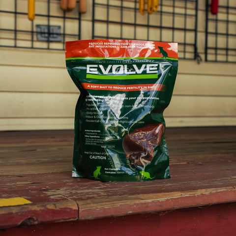 Green and orange packaging of Evolve rat control product on a red farm step