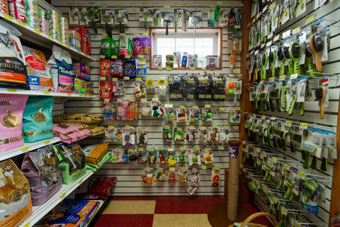 Pet supply store interior with shelves stocked with pet food and supplies.