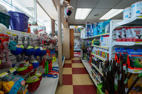 Store interior with pet supplies including toys and food on shelves.