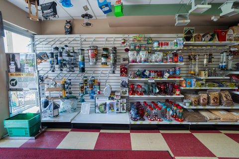 Store interior with shelves stocked with various products and a checkered floor.