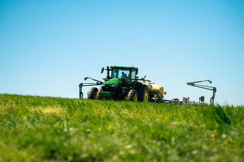 Green tractor on a grassy field with a clear blue sky