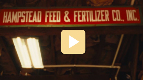 Vintage Hampstead Feed & Fertilizer Co. sign with a play button overlay