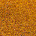 A close-up, top-down view of a textured orange-brown ladino seed mixture, filling the entire frame.