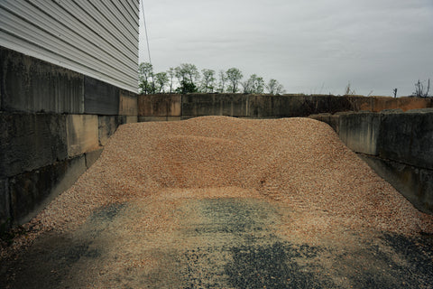 Pile of gravel or small stones next to a building with a cloudy sky.