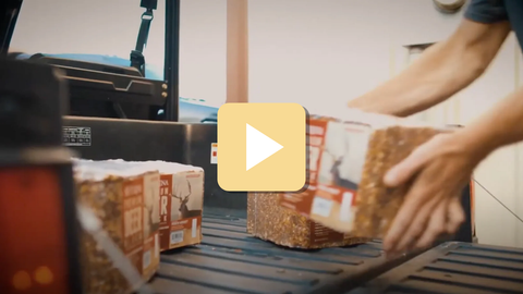 Person packaging boxes on a conveyor belt with a focus on the action.
