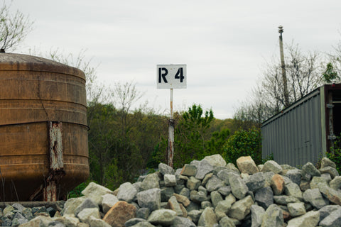 R4 signpost among rocks with a large cylindrical tank in the background