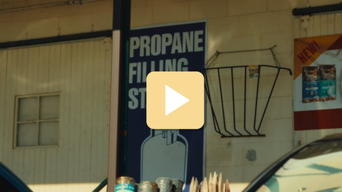 Propane filling station sign on a building exterior with a play button overlay.
