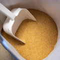 50 lb bag of The Mill Livestock Soybean Meal feed with a scoop, showing the soybean meal in a farm setting.