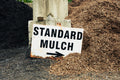 Sign pointing to standard mulch with piles of mulch in the background