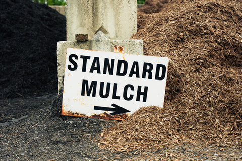 Sign pointing to standard mulch with piles of mulch in the background