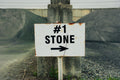 Rusticated '#1 Stone' sign on a concrete post with a blurred background