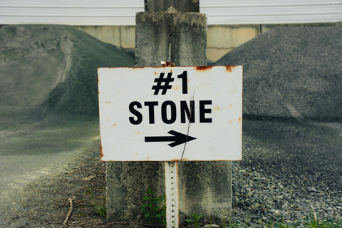 Rusticated '#1 Stone' sign on a concrete post with a blurred background
