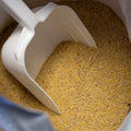 The Mill Breeder #7 Pig Feed bag showing a scoop of pig feed in a 50 lb bag, designed for pig breeders.