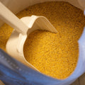 A 50 lb bag of The Mill Broiler Mash Chicken Feed with a scoop, showing poultry feed for broiler chickens.