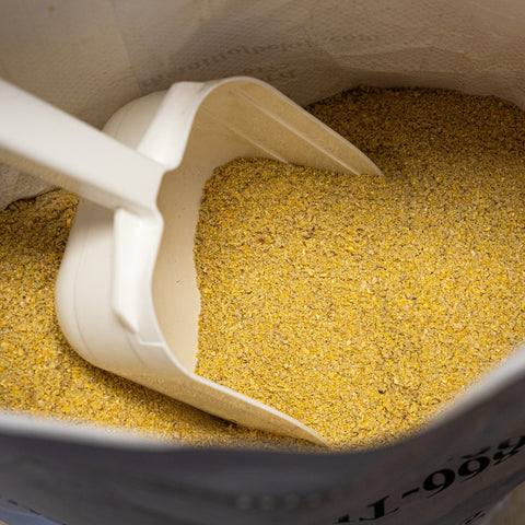 A 50 lb bag of The Mill Grower Finisher 16% pig feed meal, showing the product label and scoop for feeding pigs.