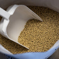 The Mill Layer Pellet Chicken Feed in a 50 lb bag, showing golden pellet poultry feed with a scoop for chickens.