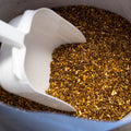 The Mill Mason Dixon Sheep and Goat Feed in a 50 lb bag, showing a scoop of the nutritious feed for livestock.