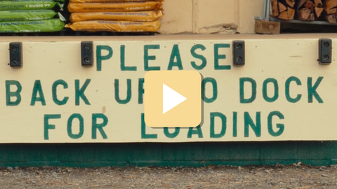 Sign directing vehicles to back up to a dock for loading, with a play button overlay.